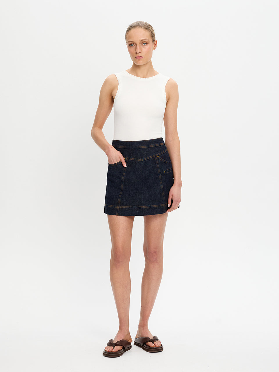 Woman wearing a white top and dark denim skirt on a white background