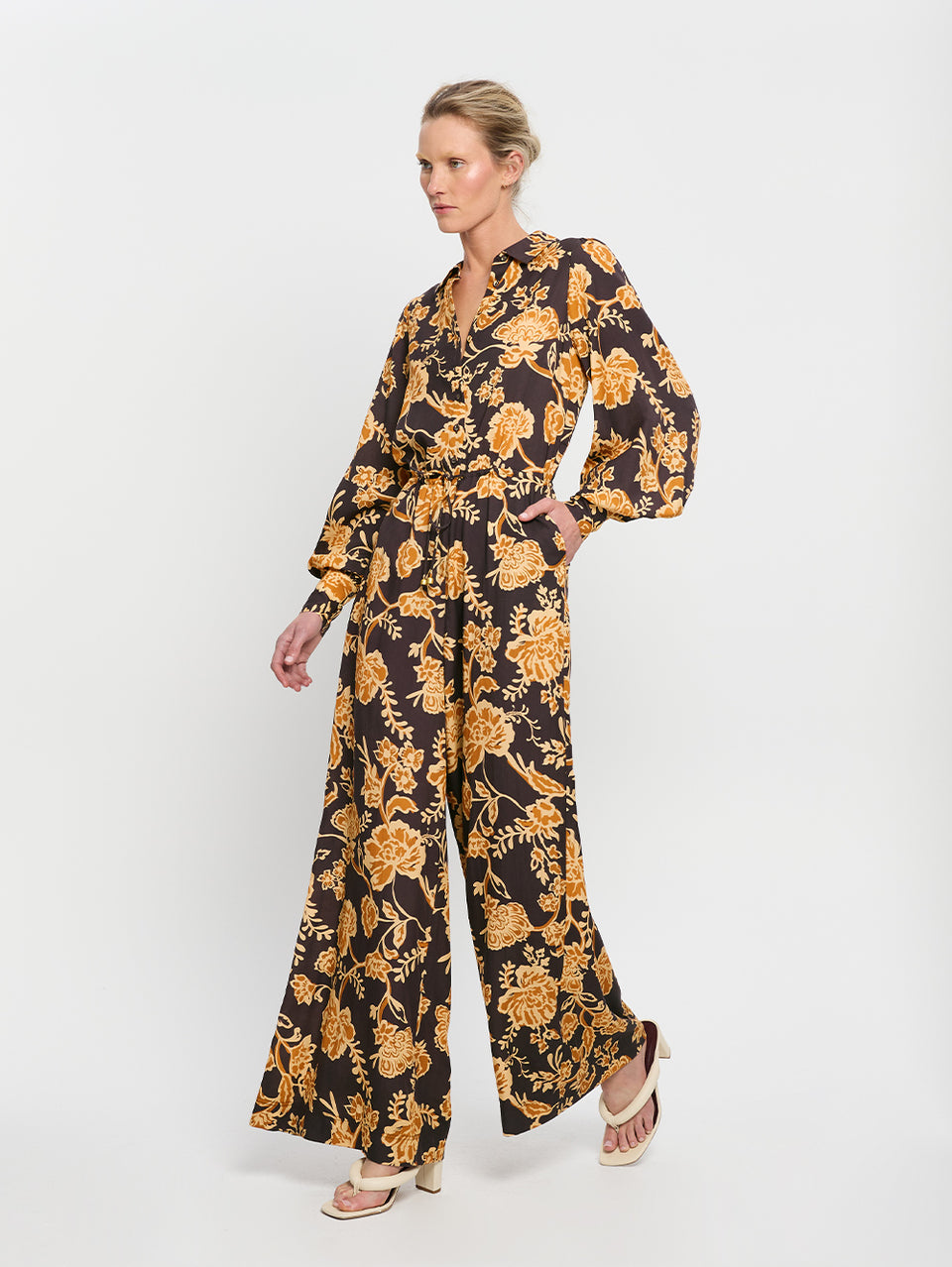 Kaia Jumpsuit KIVARI | Model wears black and orange floral jumpsuit side view