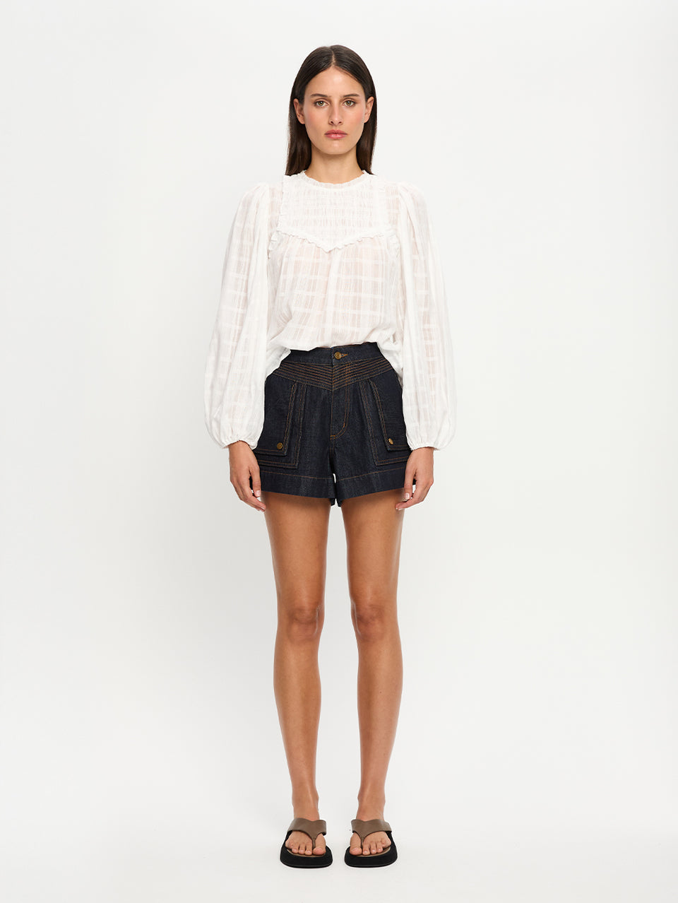 Woman wearing a white blouse and shorts on a white background