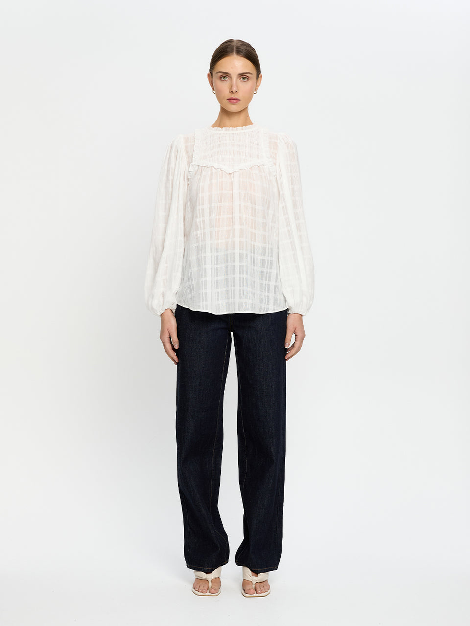 Woman wearing a white blouse and jeans on a white background