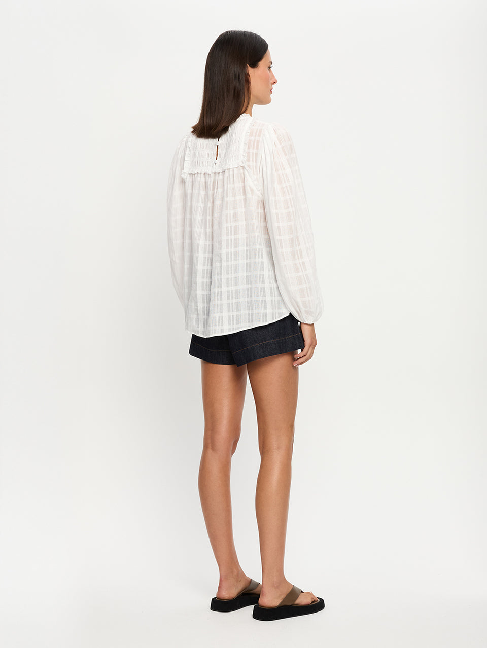 Woman wearing a white blouse and shorts on a white background