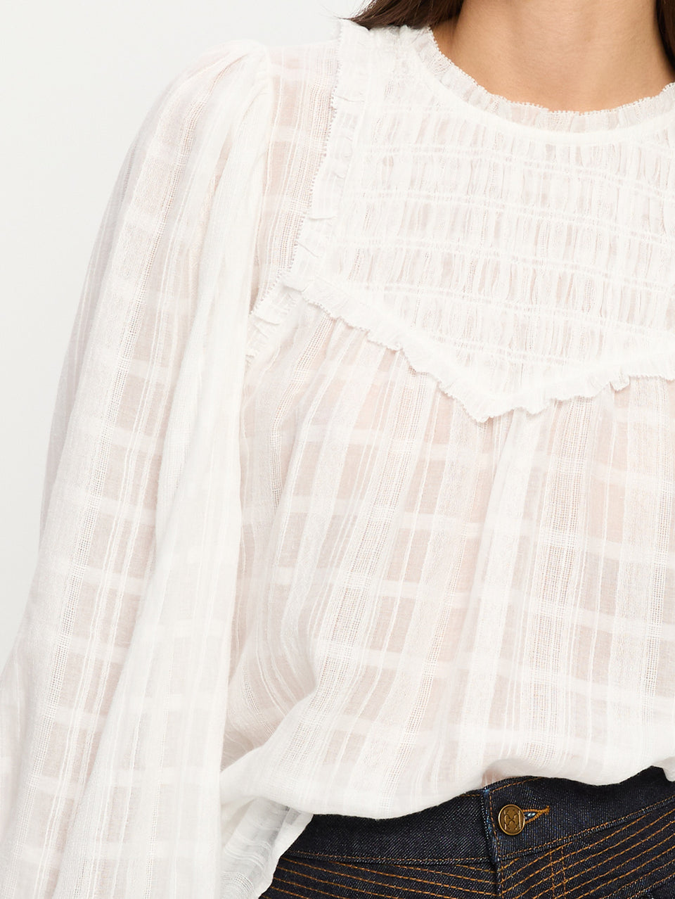 Close-up of a white textured blouse with a grey background