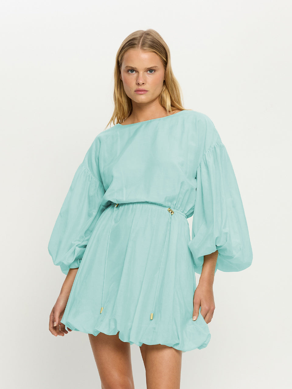 Woman wearing a light blue dress with long sleeves on a white background