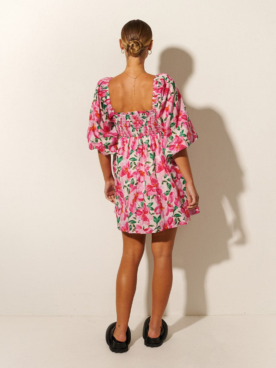 KIVARI Antonia Shirred Mini Dress | Model wearing Pink and Green Floral Mini Dress Back View