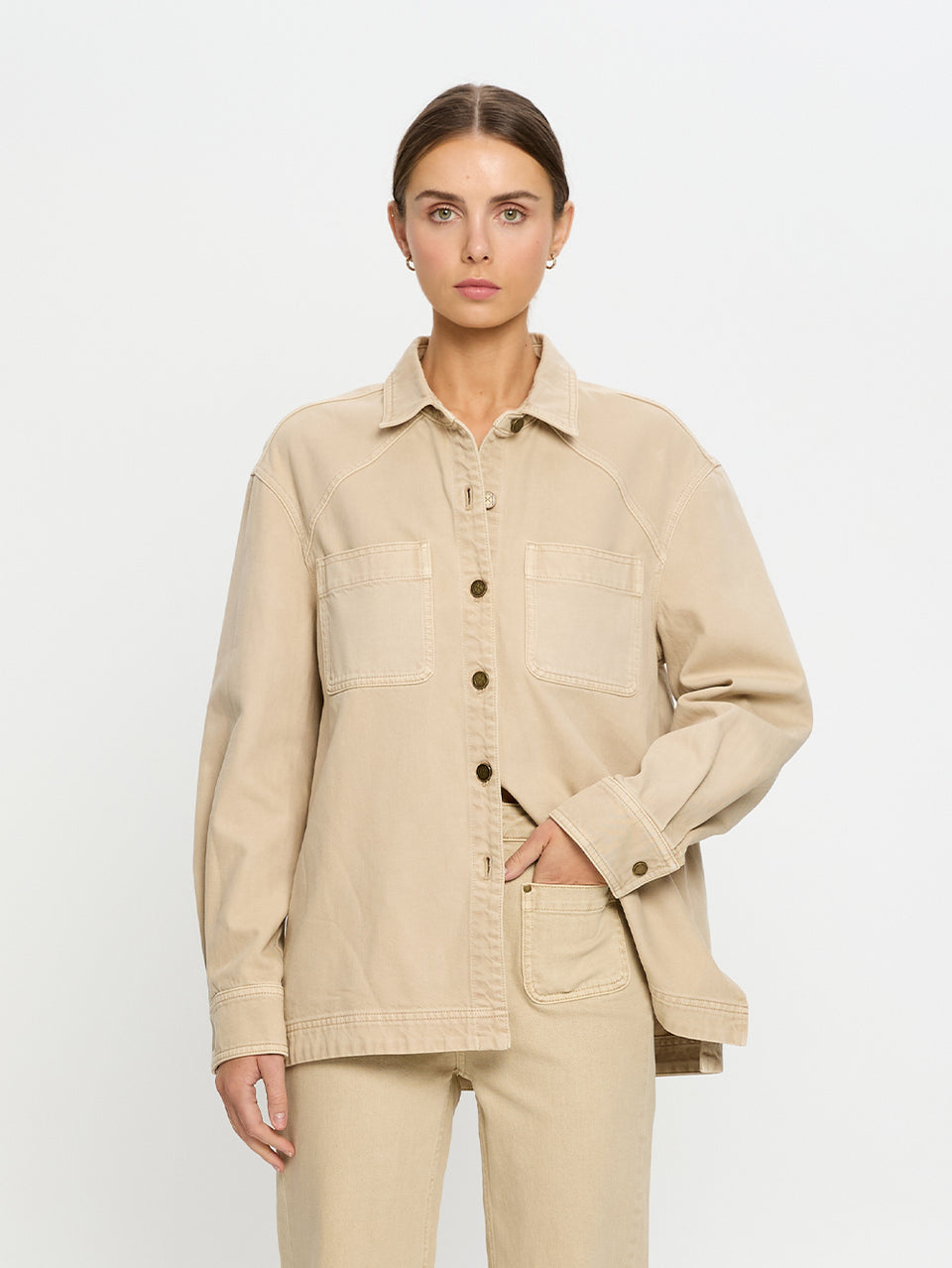 Woman wearing a beige denim shirt and jeans on a white background
