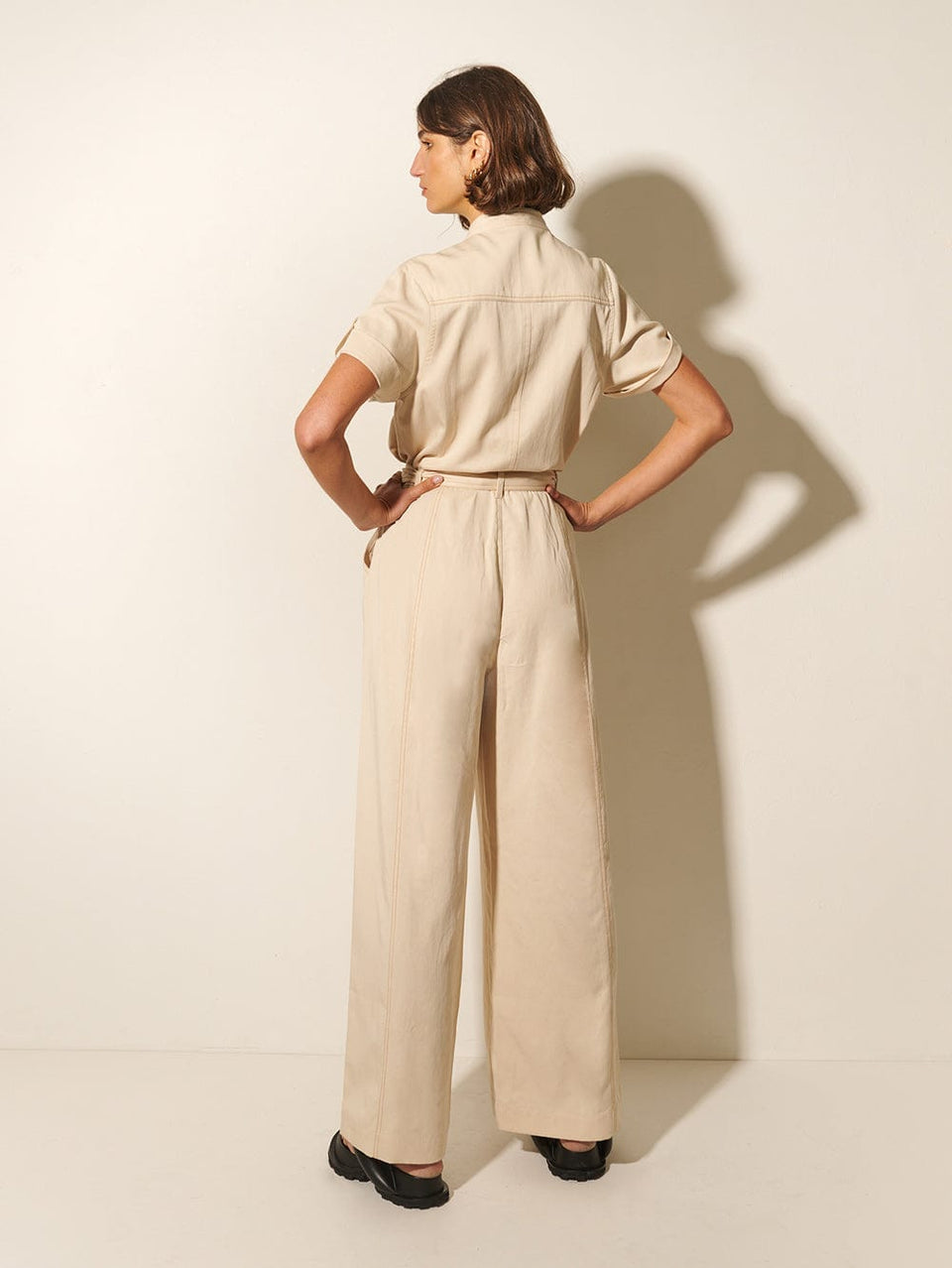 Gianna Jumpsuit KIVARI | Model wears cream short sleeve jumpsuit back view