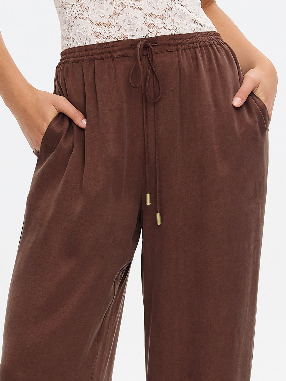 Brown wide-leg lounge pants with an elastic drawstring waist and side pockets, shown on a model against a light gray background.