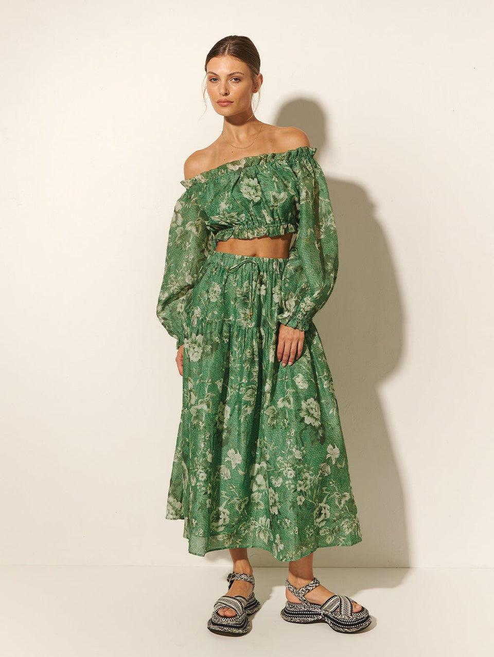 Studio model wears KIVARI Khalo Crop Top: A green floral off-the-shoulder top with full-length blouson sleeves and elasticated bust, waist and sleeve details.\