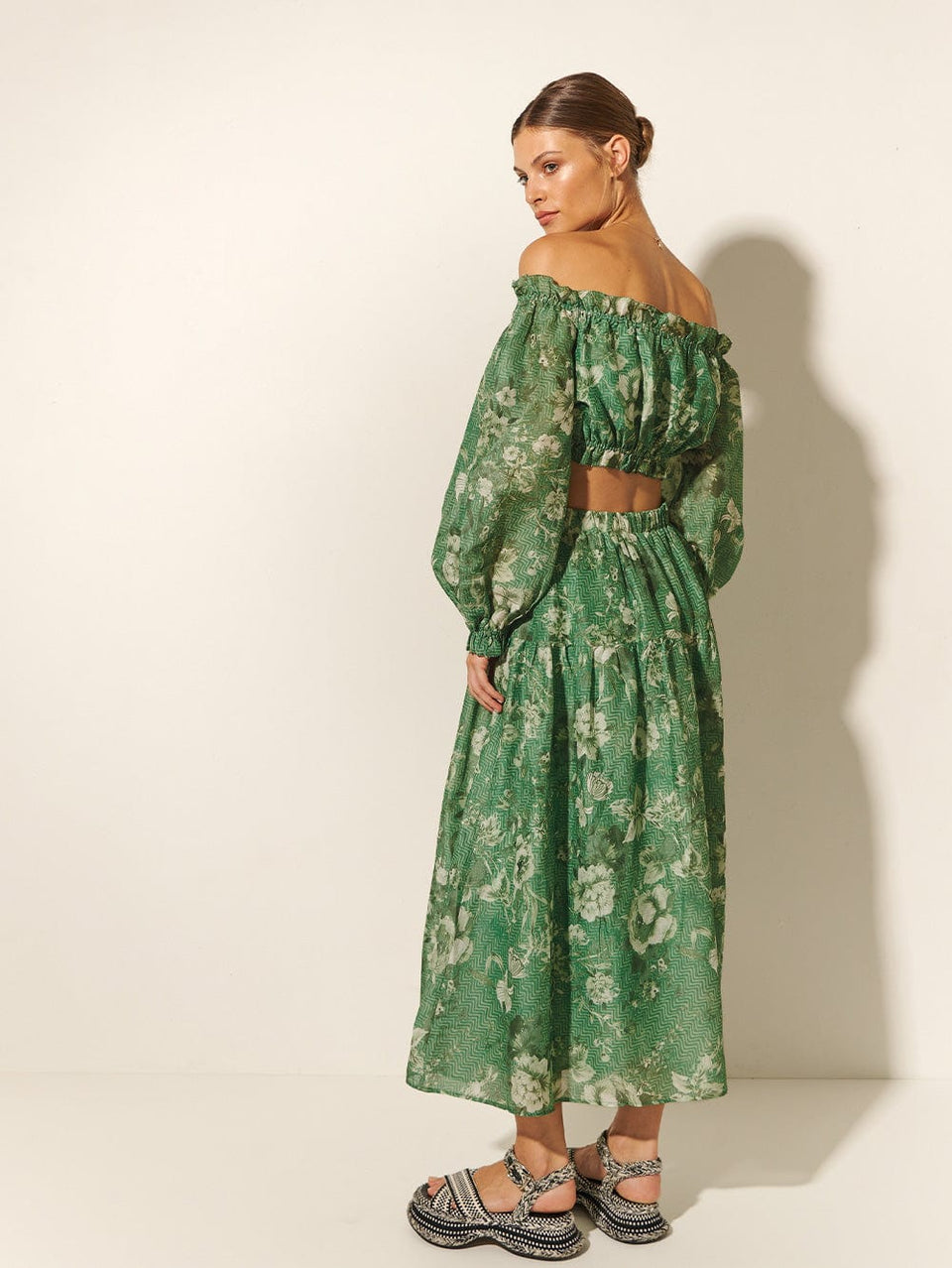 Studio model wears KIVARI Khalo Crop Top: A green floral off-the-shoulder top with full-length blouson sleeves and elasticated bust, waist and sleeve details.