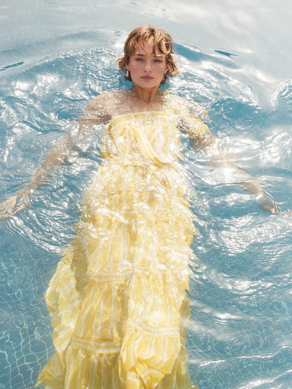 Lola Maxi Dress KIVARI | Model wears yellow and white striped maxi dress in water campaign image