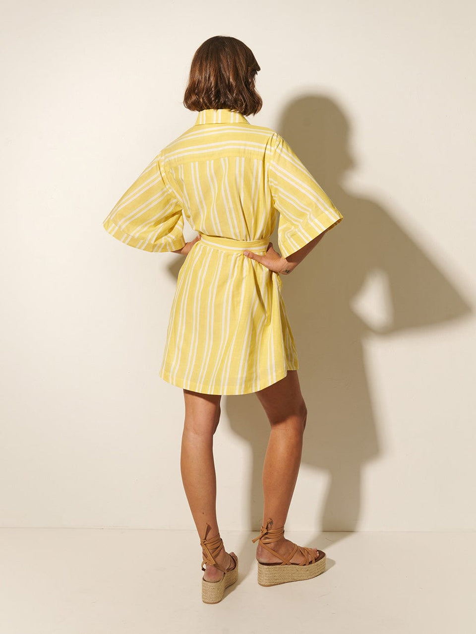 Lola Shirt Dress KIVARI | Model wears yellow and white striped shirt dress back view