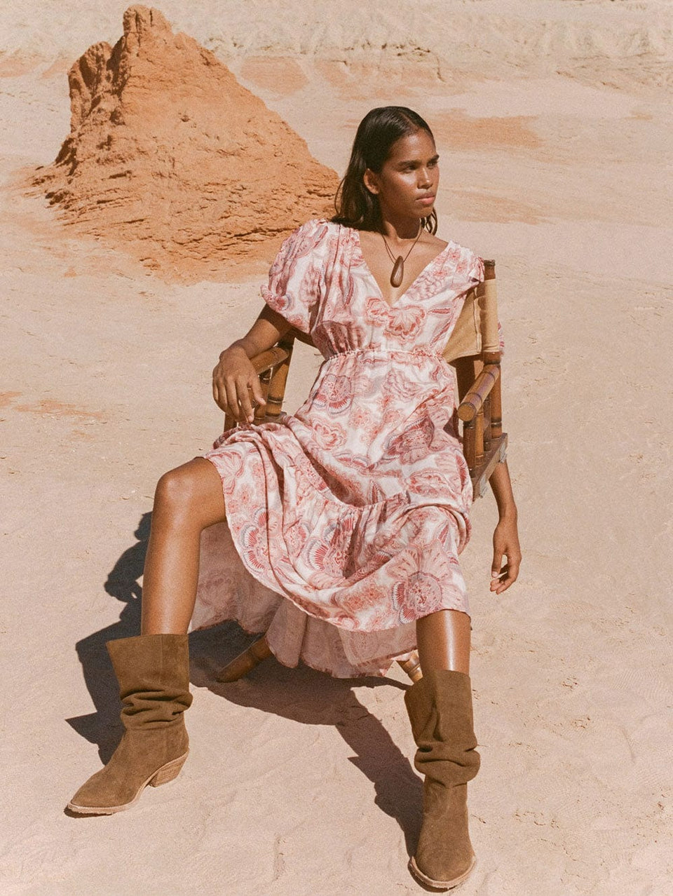 KIVARI Maya V Neck Maxi Dress | Model wearing dress sitting on chair in desert.