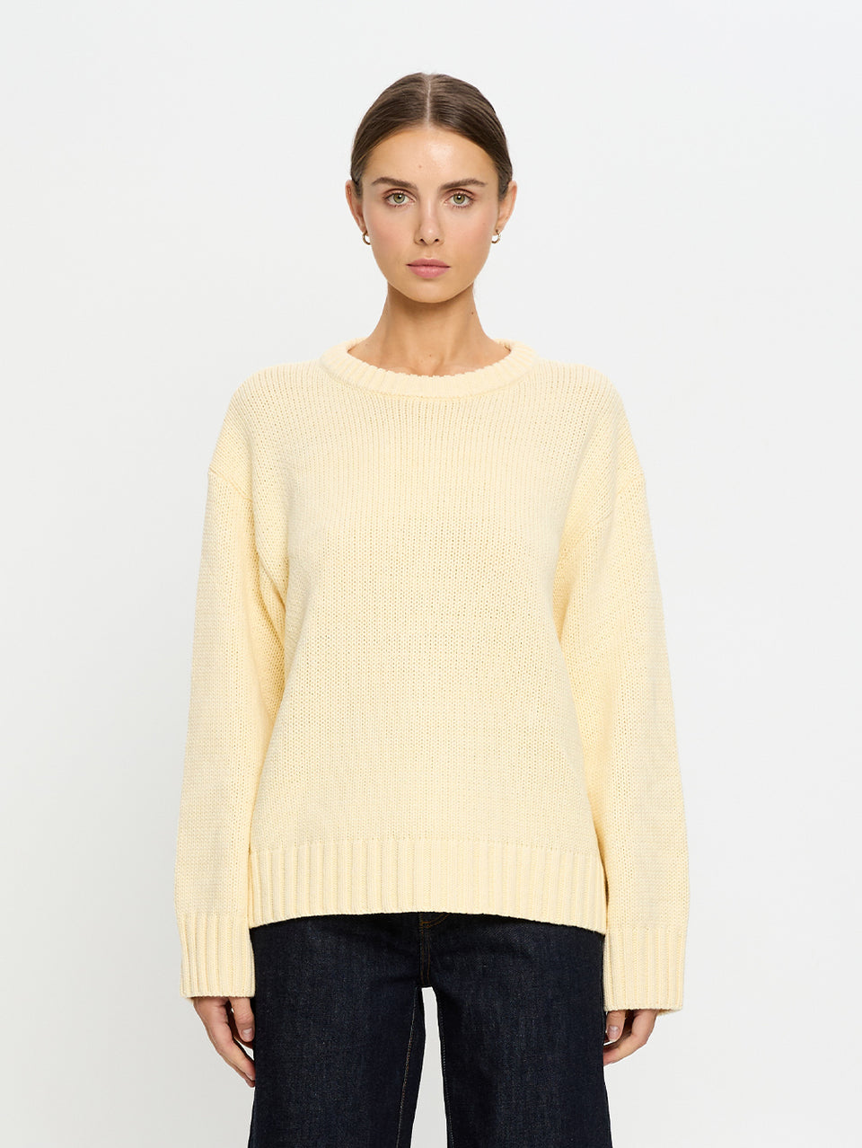 Woman wearing a light yellow sweater on a white background