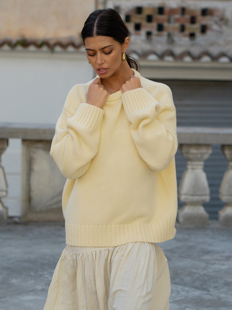 Woman wearing a light yellow sweater and skirt in an outdoor setting
