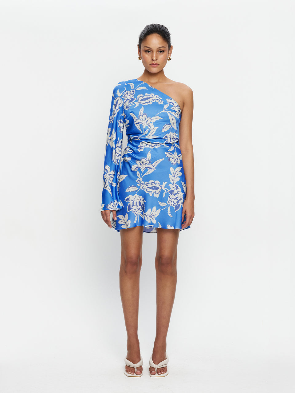 Woman wearing a blue floral one-shoulder dress on a white background