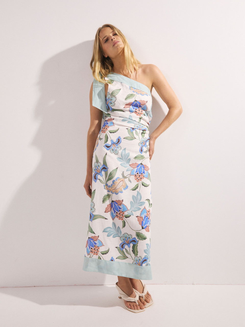 Woman wearing a floral one-shoulder dress against a white background