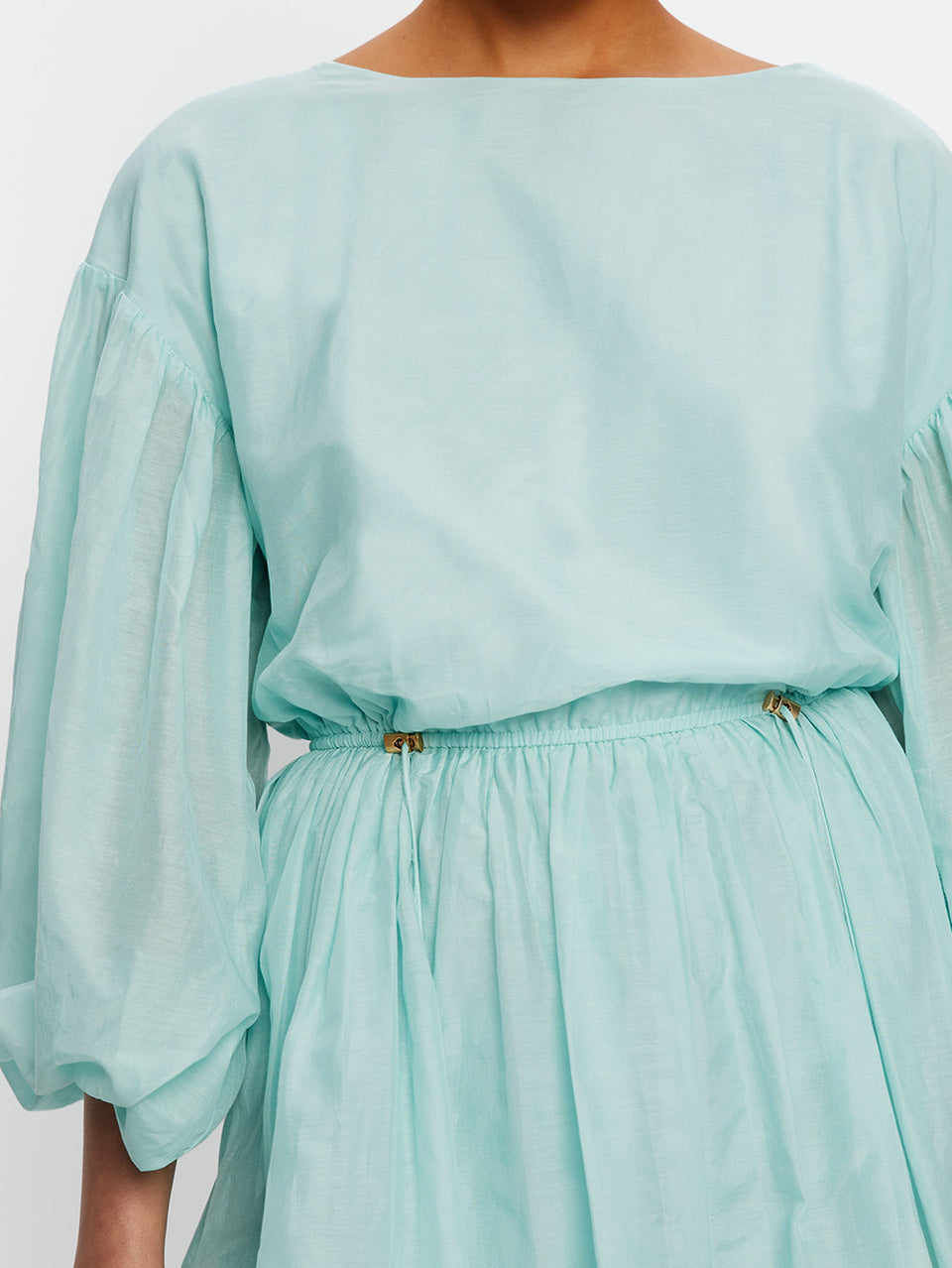 Light blue dress with long sleeves and a belt on a white background
