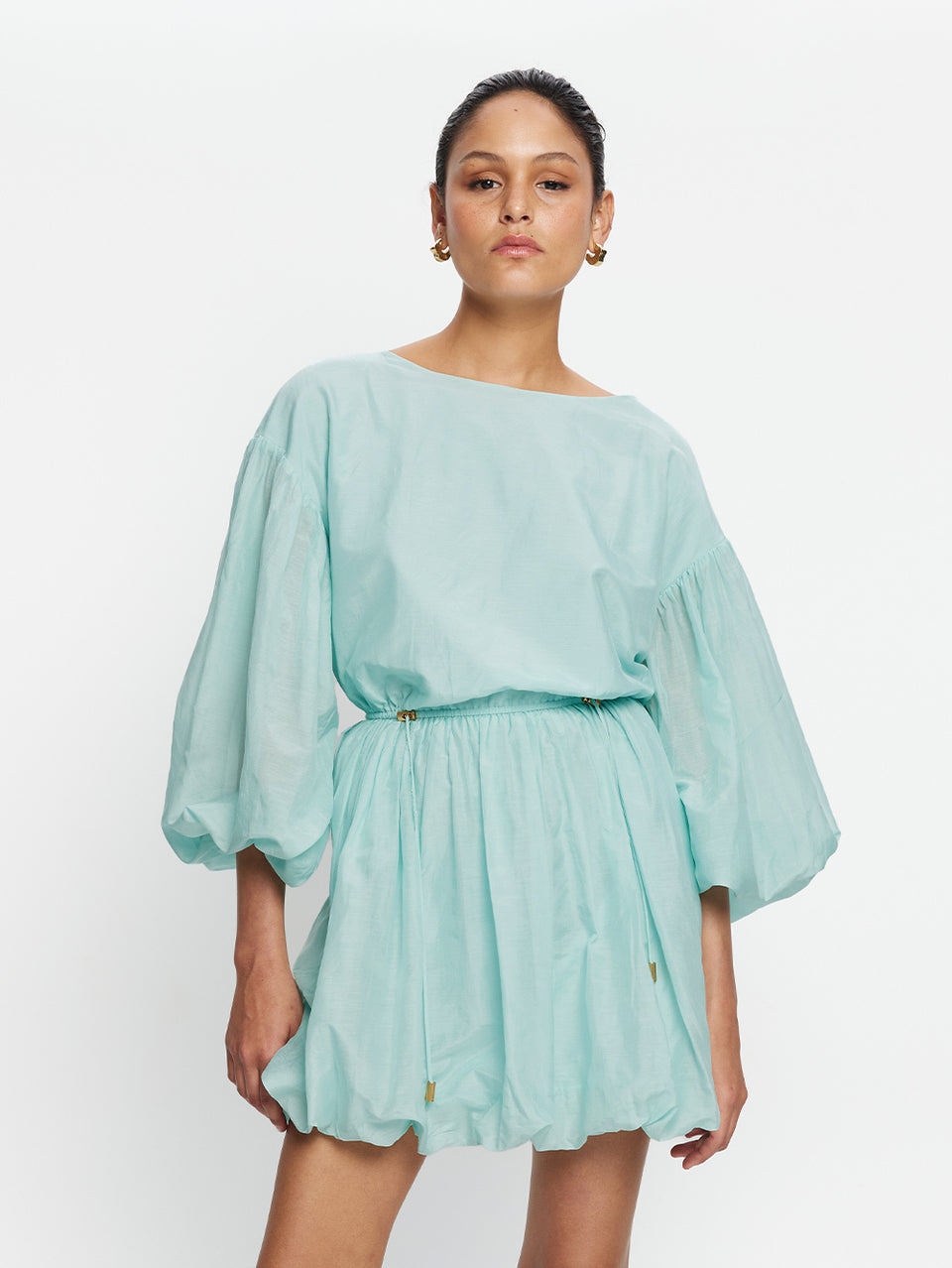 Woman wearing a light blue dress with ruffled sleeves on a white background