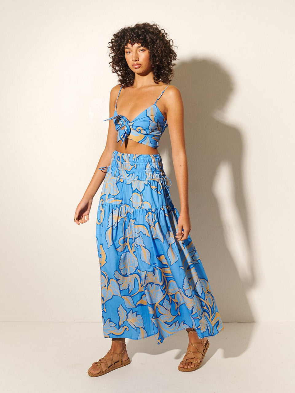 Taniana Maxi Skirt KIVARI | Model wears blue and orange floral maxi skirt with matching crop top side view 