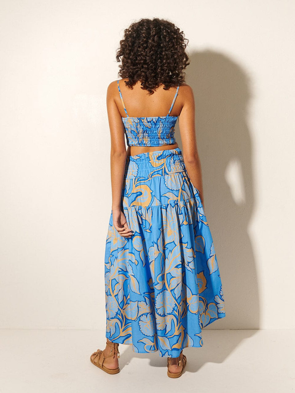 Taniana Maxi Skirt KIVARI | Model wears blue and orange floral maxi skirt with matching crop top back view